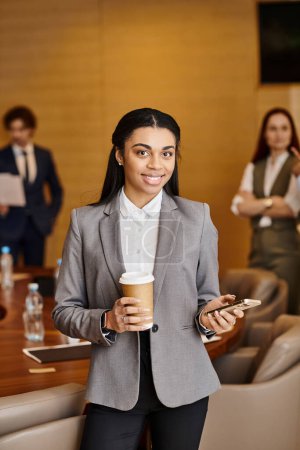 A confident woman in a business suit enjoys a cup of coffee.