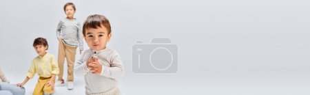Téléchargez les photos : Un groupe diversifié d'enfants, se tiennent l'un à côté de l'autre dans un studio sur fond gris. - en image libre de droit