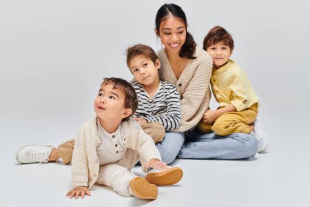 Una joven madre asiática se sienta en el suelo con los niños, creando un momento sereno de unidad y conexión.