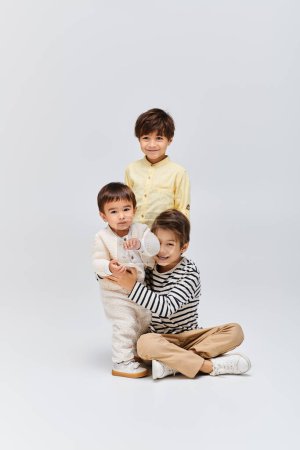 A diverse group of asian children posing together in a studio setting on a grey background.