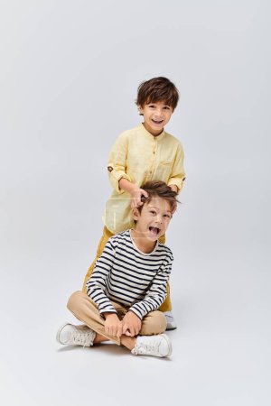 Foto de Two young boys, sitting on the ground, are in awe with their mouths wide open in a studio setting - Imagen libre de derechos