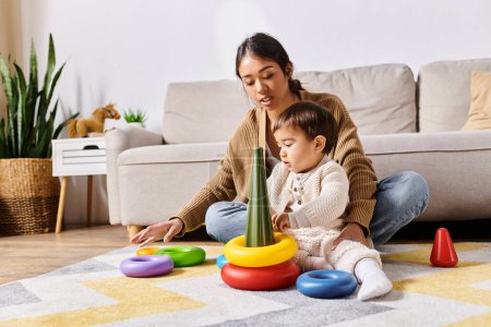 Una joven madre asiática juega alegremente con su pequeño hijo en el suelo de su sala de estar.