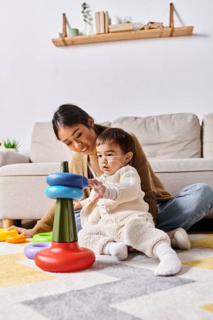 A young Asian mother joyfully interacts with her little son, playing together on the floor in their cozy living room.