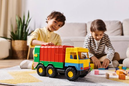 Zwei kleine Jungen spielen fröhlich auf dem Boden mit einem Spielzeug-LKW im Wohnzimmer.