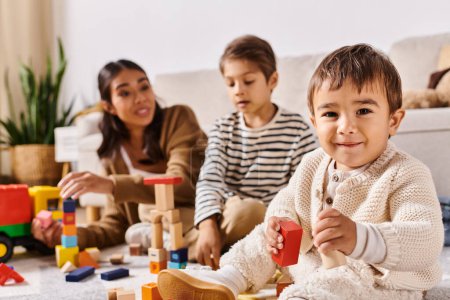 Téléchargez les photos : A group of children, including a young Asian mother and her little sons, playing happily with wooden toys in a cozy living room. - en image libre de droit
