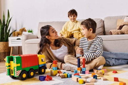 Eine junge asiatische Mutter sitzt auf dem Boden und spielt fröhlich mit ihren kleinen Söhnen im gemütlichen Wohnzimmer ihres Hauses.