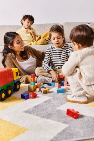 Una joven madre asiática jugando felizmente con sus hijos pequeños en el suelo de sus hogares sala de estar.