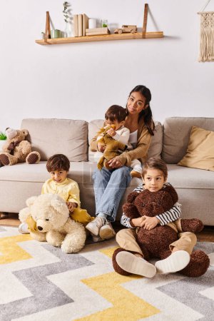 Eine junge asiatische Mutter sitzt auf einer Couch neben ihren kleinen Söhnen im heimischen Wohnzimmer.