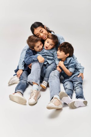 Téléchargez les photos : A group of children, including a young Asian mother and her little sons, sitting on top of each other in a playful and creative manner. - en image libre de droit