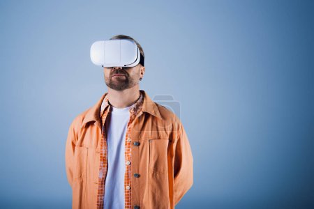 A man in an orange shirt explores the metaverse in a white virtual reality headset within a studio setting.