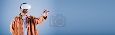 Photo for A man in an orange shirt in a studio setting, immersed in the virtual reality experience. - Royalty Free Image