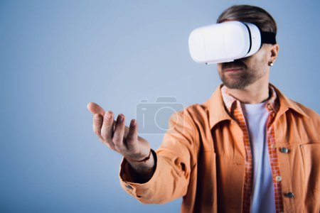 A man in an orange shirt is immersed in the metaverse as he experiences virtual reality in a studio setting.