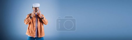 Photo for A man in a virtual reality headset explores the digital world while standing in front of blue background. - Royalty Free Image