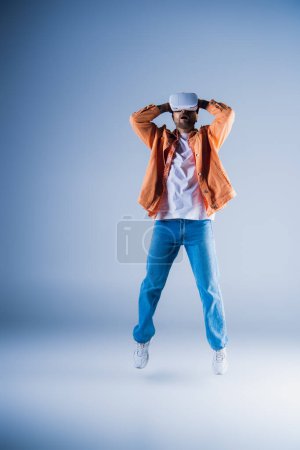 Foto de Un hombre con un casco VR con las manos en la cabeza, sintiéndose abrumado en un ambiente de estudio. - Imagen libre de derechos