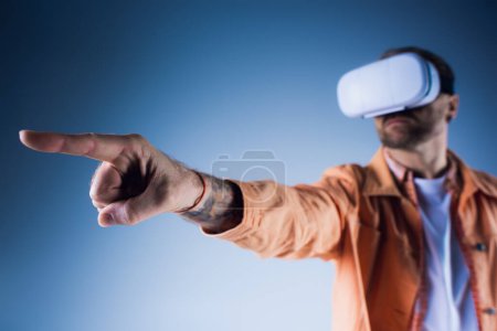 Ein Mann mit Hut zeigt in einem Virtual-Reality-Headset im Studio auf etwas.
