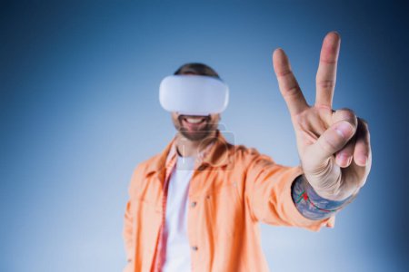 Téléchargez les photos : Un homme en chemise orange portant un bandeau dans un studio, explorant les limites de la réalité à travers la réalité virtuelle. - en image libre de droit