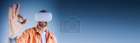 Téléchargez les photos : Un homme en chemise orange, les yeux bandés, pose en studio avec un casque de réalité virtuelle, explorant la métaverse. - en image libre de droit