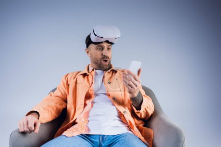 A man immersed in the virtual world, sitting in a chair with a cell phone in hand, blending realities in a studio setting.