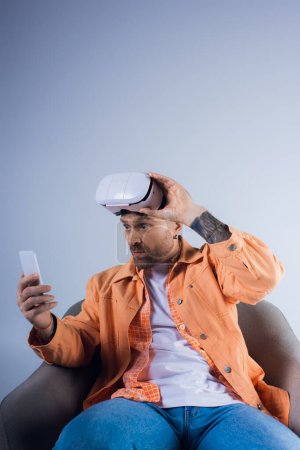 Ein Mann, der in die virtuelle Welt eingetaucht ist, auf einem Stuhl sitzend, das Handy in der Hand.