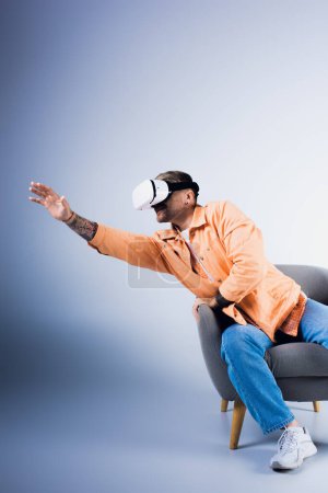 A man in a VR headset sits in a chair with his hand raised, immersed in a virtual world