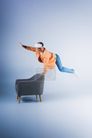 Téléchargez les photos : Un homme dans un casque VR effectue un tour défiant la gravité sur une chaise dans un cadre futuriste studio. - en image libre de droit