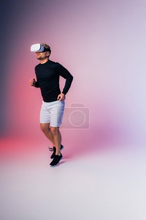 Foto de Un hombre con una camisa negra y pantalones cortos blancos se mueve con gracia en un entorno de estudio, la realidad virtual - Imagen libre de derechos
