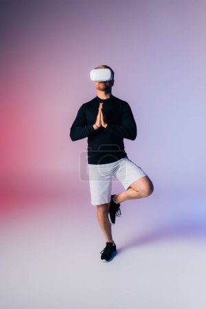 A man in a black shirt and white shorts gracefully strikes a yoga pose in a studio setting.