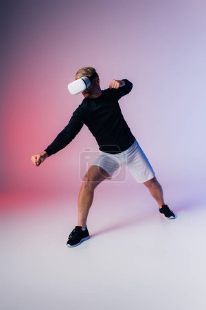 Photo for A man clad in a black shirt and white shorts explores the immersive Metaverse within a studio setting. - Royalty Free Image