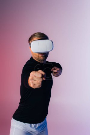 Un hombre con una camisa negra y pantalones cortos blancos, con los ojos vendados, se encuentra inmerso en la experiencia metaversa en un estudio de realidad virtual.