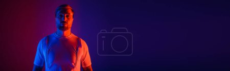 Photo for A man in smart glasses stands confidently in a studio, set against a vibrant red and blue background. - Royalty Free Image