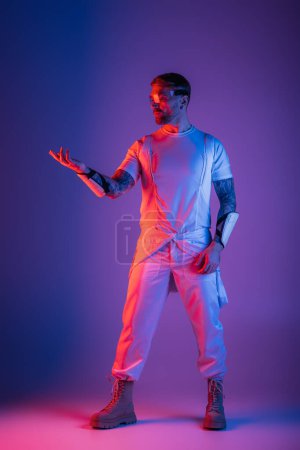 Un hombre vestido con una prístina camisa blanca y pantalones está de pie con confianza en un estudio de realidad virtual, su presencia emanando elegancia.