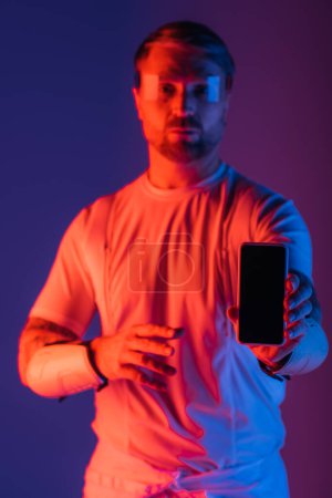 Ein Mann mit intelligenter Brille hält ein Handy in der Hand, eingetaucht in die virtuelle Realität des Metaverse in einem Studio-Setting.