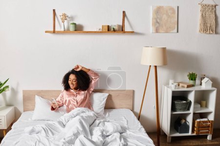 Une afro-américaine frisée en pyjama repose paisiblement sur un lit avec des draps blancs dans sa chambre.