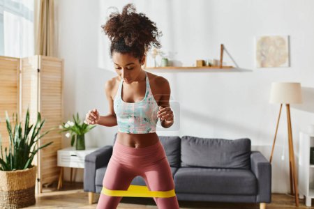 Curly African American woman in sports bra and leggings exercises at home, showcasing strength and dedication.
