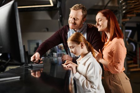 Three people, a happy family, gathered around a computer screen, engrossed in what they see.