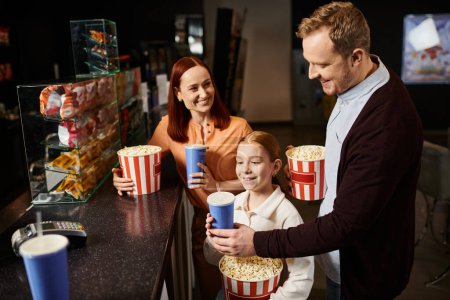 Eine glückliche Familie mit einem Mann, einer Frau und einem Kind beim gemeinsamen Kinobesuch.