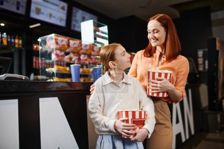 Téléchargez les photos : A woman and daughter stand side by side, radiating joy and togetherness, sharing a special moment in the cinema. - en image libre de droit