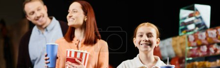 Téléchargez les photos : A cheerful family enjoying quality time together at the cinema, standing side by side with beaming smiles. - en image libre de droit