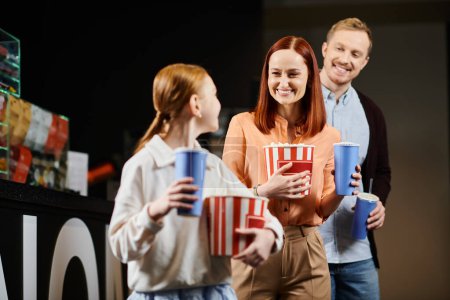 Une famille heureuse se tient ensemble au cinéma, profitant de la compagnie des autres.