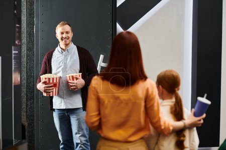 A happy family stands in a circle at the cinema, enjoying each others company while waiting for the movie to start.
