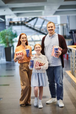 Familie hält fröhlich Popcornboxen in der Hand, genießt den Kinobesuch.
