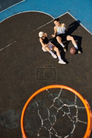 Dos jóvenes se levantan triunfalmente sobre una cancha de baloncesto, celebrando su victoria con sonrisas en un soleado día de verano.