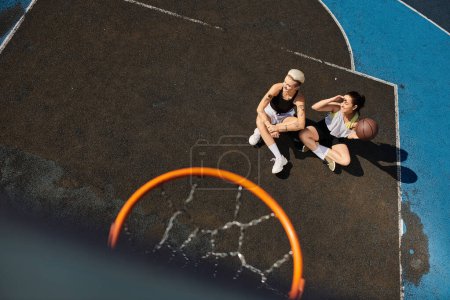 Two young women enjoy a game of basketball on a sunny outdoor court.