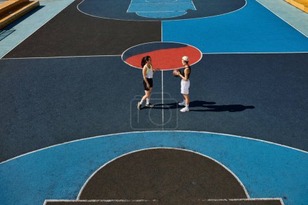 Młode kobiety umiejętnie grają w koszykówkę na dworze na świeżym powietrzu, pokazując latem swój atletyzm i przyjaźń.