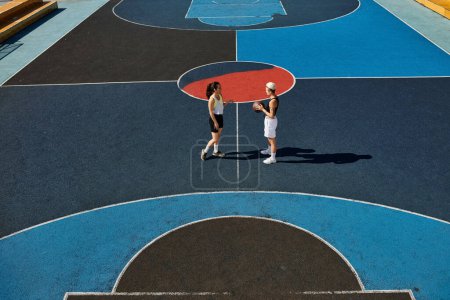 Young women skillfully play basketball on a court outdoors, showcasing their athleticism and friendship in the summer.