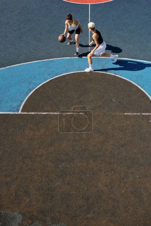 mujeres jóvenes jugando al baloncesto en una cancha al aire libre, participando en un juego competitivo y enérgico.