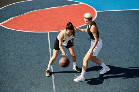 Zwei athletische junge Frauen stehen stolz auf einem Basketballfeld und strahlen an einem sonnigen Tag Zuversicht und Sportlichkeit aus.