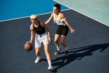 Deux jeunes femmes, amies, se tiennent fièrement au sommet d'un terrain de basketball, incarnant force et esprit sportif au soleil d'été.