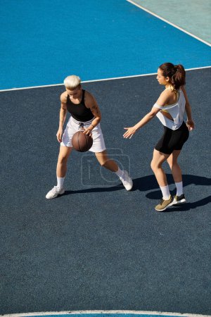 Mujeres jóvenes atléticas jugando al baloncesto al aire libre en un día soleado, mostrando sus habilidades y trabajo en equipo.