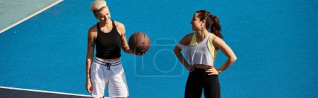 Photo for Two athletic female friends stand proudly on top of a tennis court, basking in the summer sunlight. - Royalty Free Image